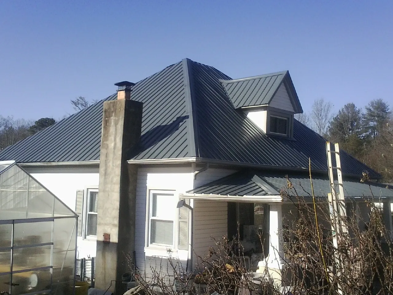 Dark blue standing seam metal roof on a white farmhouse with dormer — Slate & Tile Roof Repair by Roofing Brothers in Hyndman