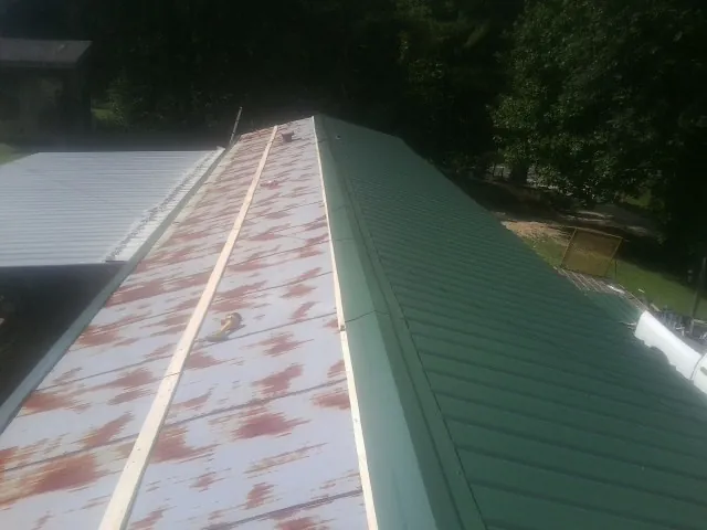 Old rusted panels beside newly installed green metal roofing — Wind Damage Roof Repair by Roofing Brothers in Hyndman