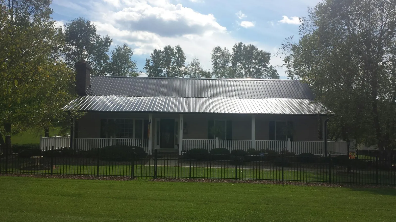 Gray metal roof on a brick ranch with a full width front porch — Gutter Guard Installation work by our crew in Hyndman