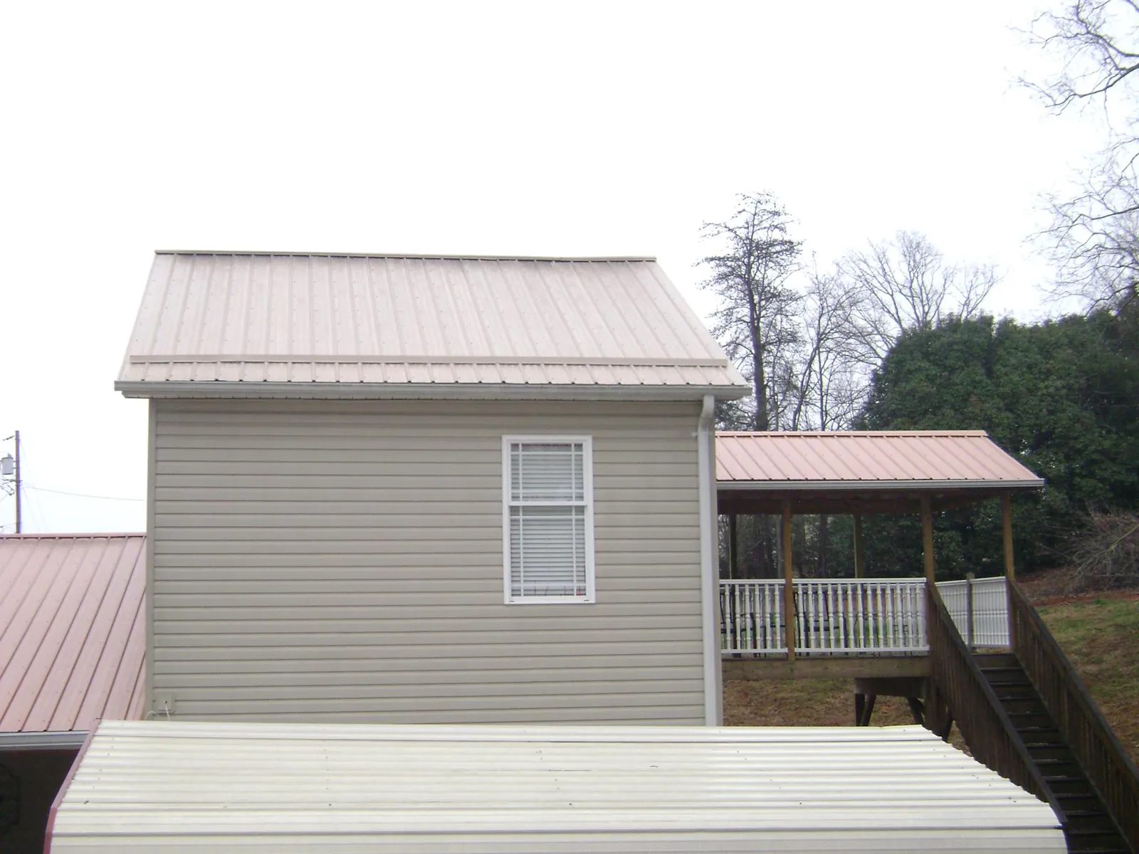 Tan metal roofs on a two story addition and attached porch, from a Roof Replacement job in Hyndman