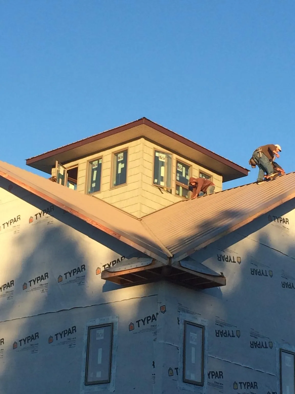Roofers working around a rooftop cupola on a new metal roof at sunset — Roof Waterproofing in Hyndman by Roofing Brothers
